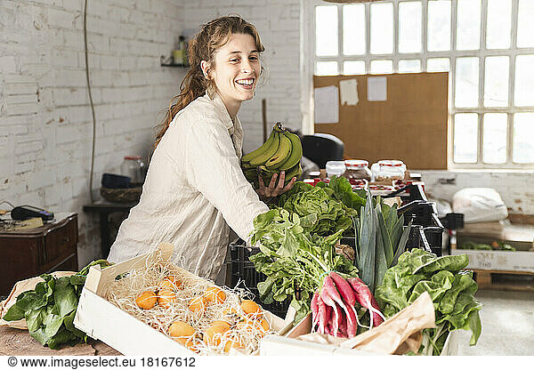 Happy owner picking up vegetables in greengrocer shop