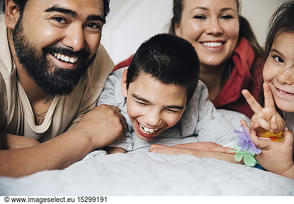 Happy parents with children lying on bed at home