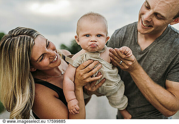 Happy parents with cute baby son making funny face