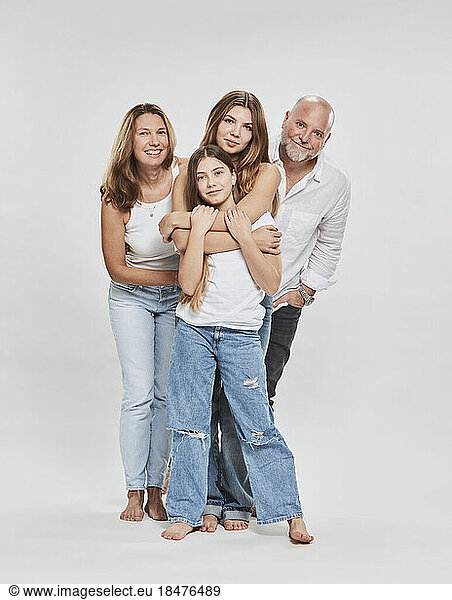 Happy parents with daughter standing together against white background