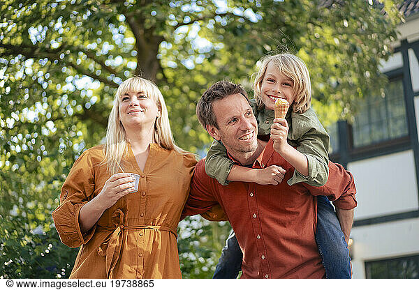 Happy parents with son enjoying ice cream on sunny day