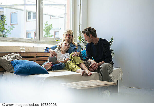 Happy parents with son sitting on sofa at home