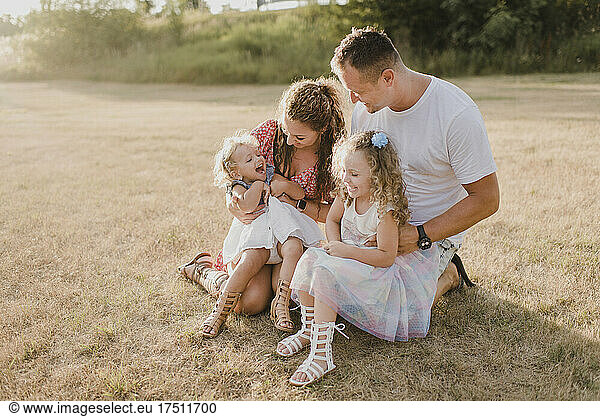 Happy parents with two daughters on a meadow