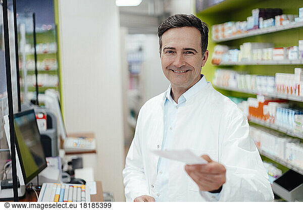 Happy pharmacist showing prescription at store