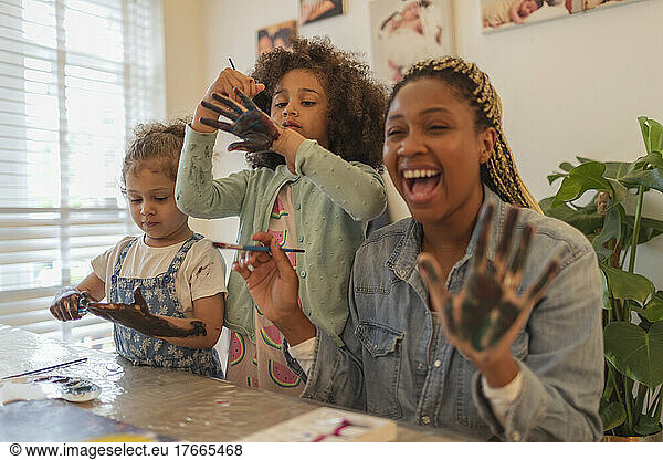 Happy playful mother and daughters finger painting