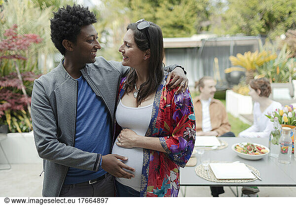 Happy pregnant couple hugging on patio