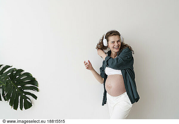 Happy pregnant woman enjoying listening to music