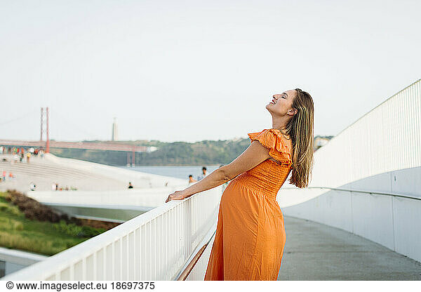Happy pregnant woman holding railing