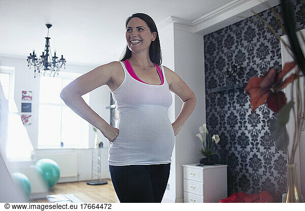 Happy pregnant woman in tank top at home