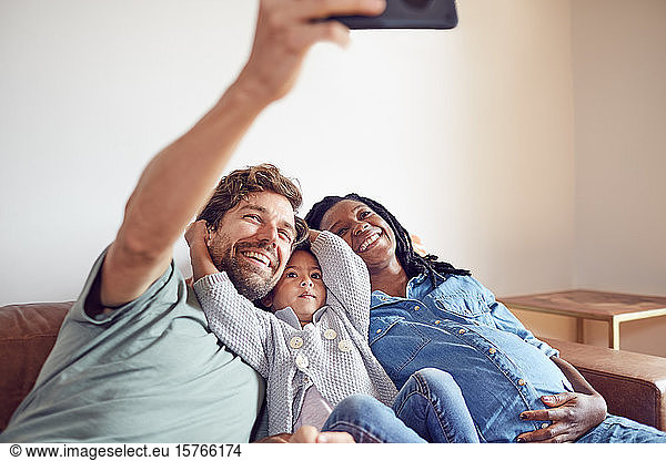 Happy pregnant young family taking selfie