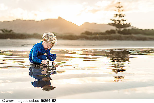 Happy preschooler playing at beach at dusk