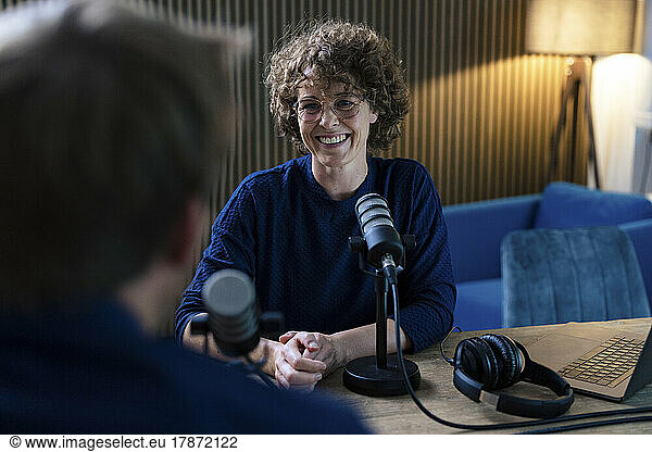 Happy presenter interviewing guest in recording studio