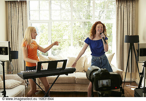 Happy preteen girl friends singing and playing keyboard piano