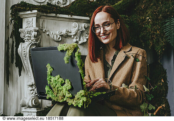 Happy redhead businesswoman working on laptop