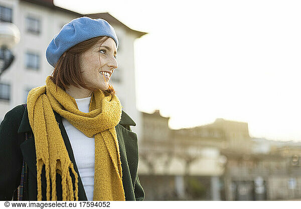 Happy redhead woman wearing yellow scarf and blue beret