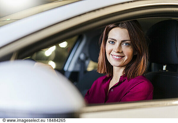 Happy redheaded businesswoman driving car