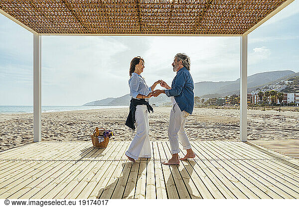 Happy senior couple dancing at beach on weekend