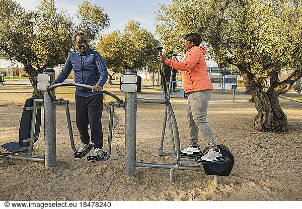 Happy senior couple exercising at outdoor equipment at park