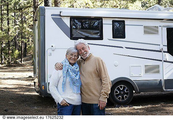 Happy senior couple standing in front of motor home