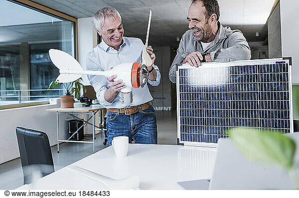 Happy senior engineer working by colleague with solar panel at office