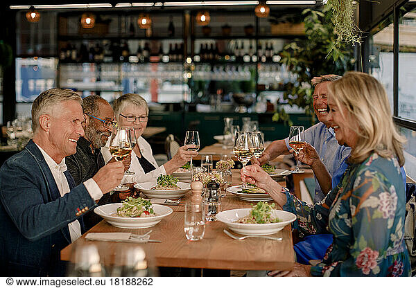 Happy senior male and female friends toasting wineglasses in restaurant