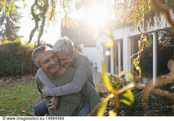 Happy senior man carrying wife piggyback in garden