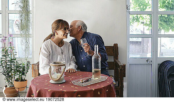 Happy senior man embracing woman sitting in restaurant