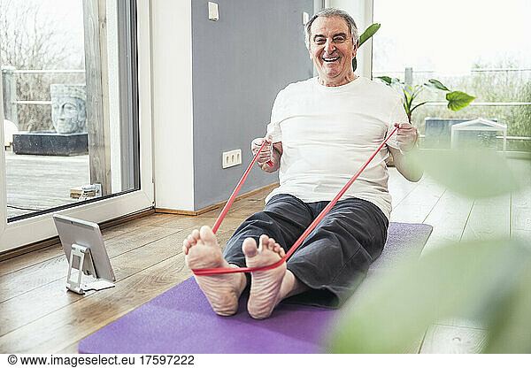 Happy senior man with resistance band doing workout at home