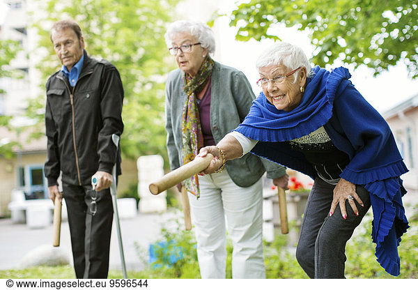 Happy senior people playing kubb game at park
