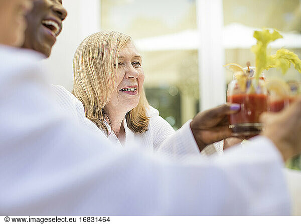 Happy senior woman enjoying bloody mary cocktail with friends