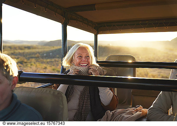 Happy senior woman on safari riding in off-road vehicle