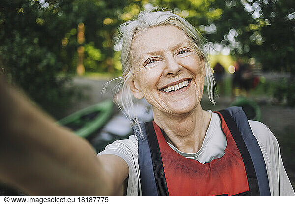 Happy senior woman taking selfie wearing life jacket