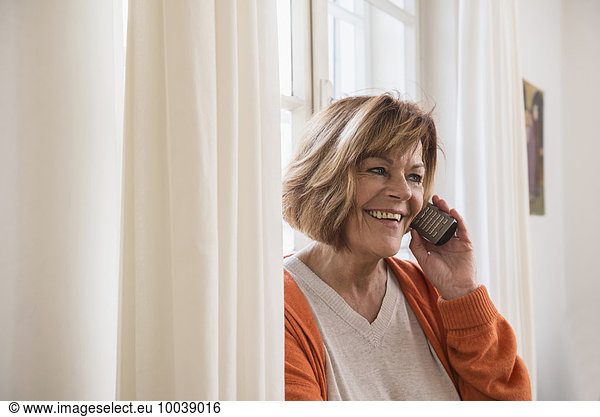 Happy senior woman talking on cell phone at home  Munich  Bavaria  Germany
