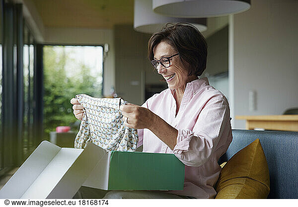 Happy senior woman unboxing package at home