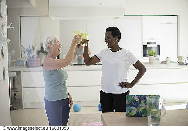 Happy senior women friends drinking water after workout at home