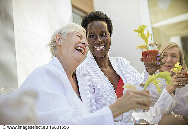 Happy senior women friends enjoying bloody mary cocktails