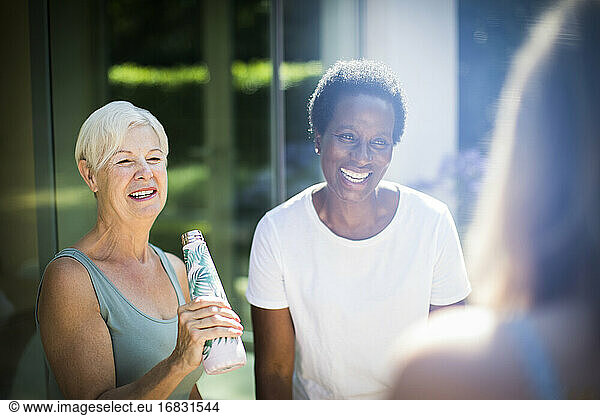 Happy senior women friends laughing on sunny summer patio