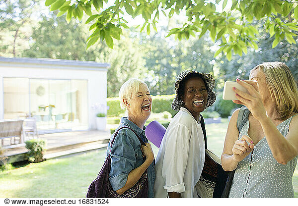 Happy senior women friends taking selfie in summer garden