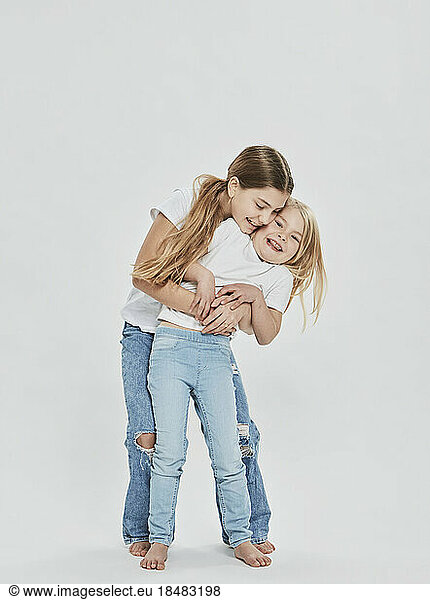 Happy sisters having fun against white background