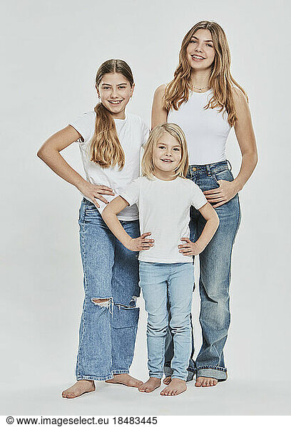 Happy sisters wearing casual clothing against white background