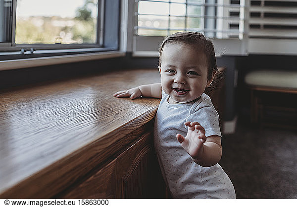 Happy smiling baby with two teeth standing by window