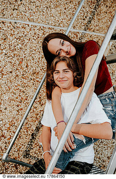 happy smiling teen boy and teen girl sitting on stairs