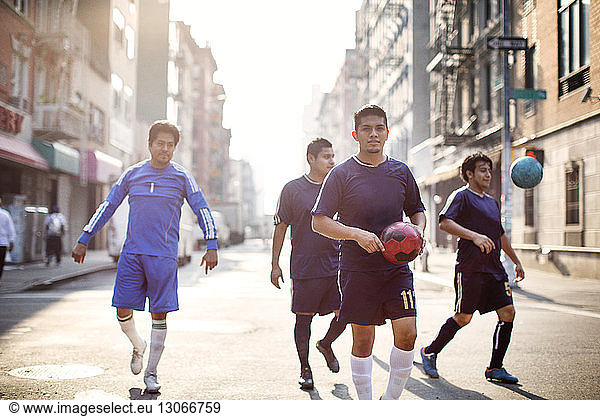 Happy soccer players walking at city street