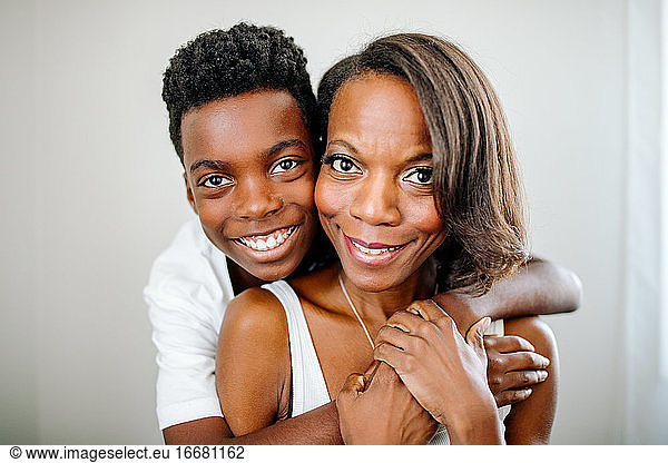 Happy son hugging pretty African American mom from behind