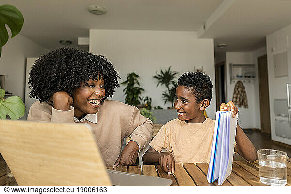 Happy son showing homework to mother at home