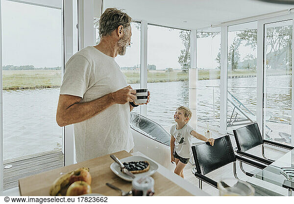 Happy son with father holding coffee cup at home