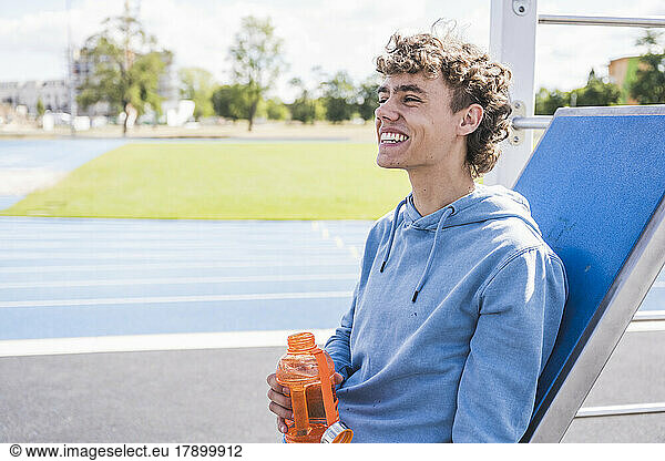 Happy sportsman holding water bottle on sunny day