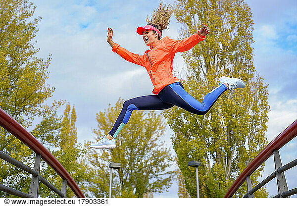 Happy sportswoman jumping in park