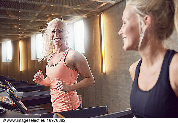 Happy sportswomen running on treadmills