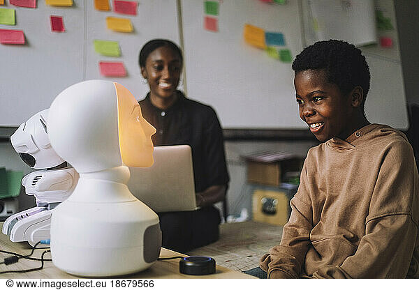 Happy student communicating with illuminated social robot at innovation lab